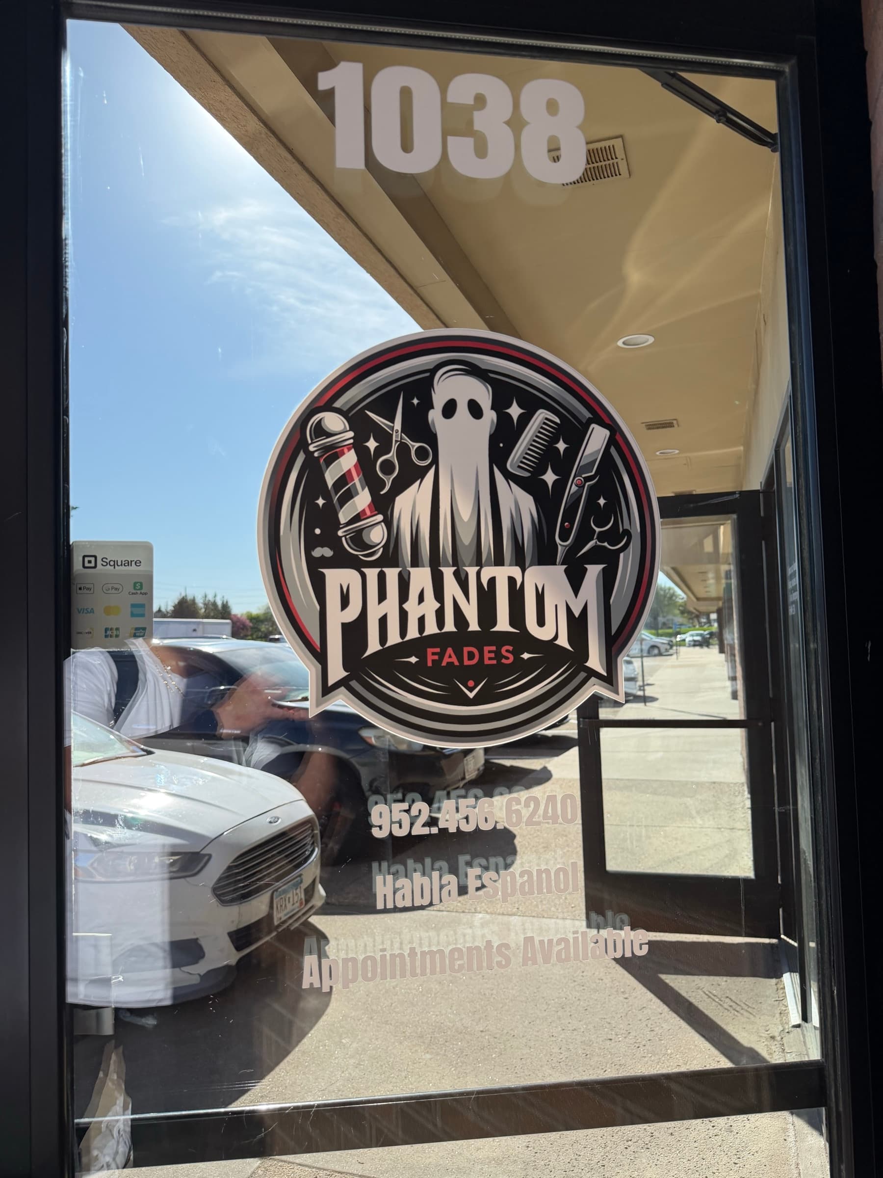 Phantom Fades storefront window with the phantom shield logo and address.
